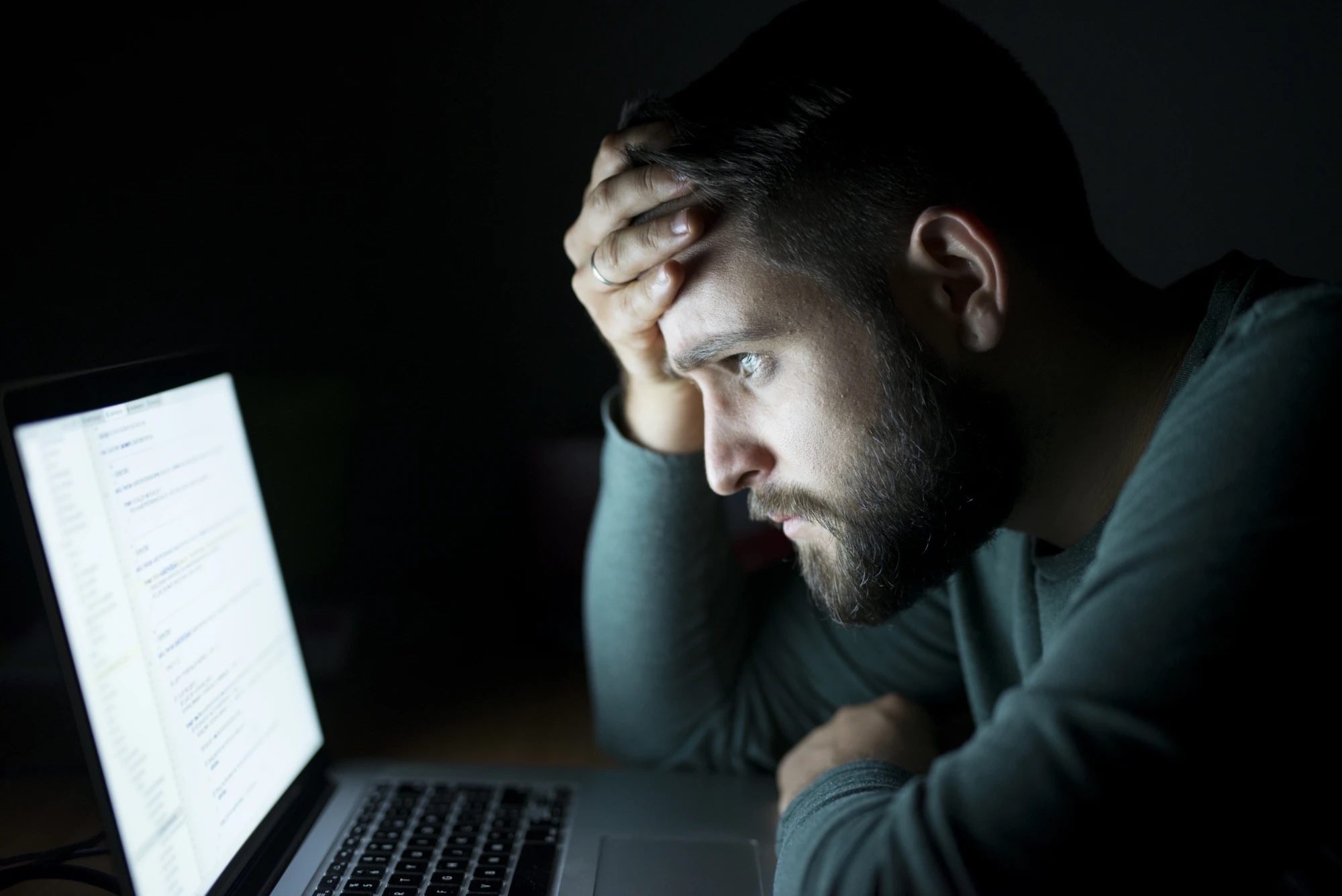 Imprenditore preoccupato davanti al computer di notte mentre controlla una notifica di sicurezza